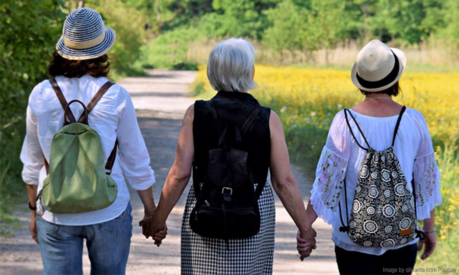 Three elderly women taking stroll in park enjoying life after menopause