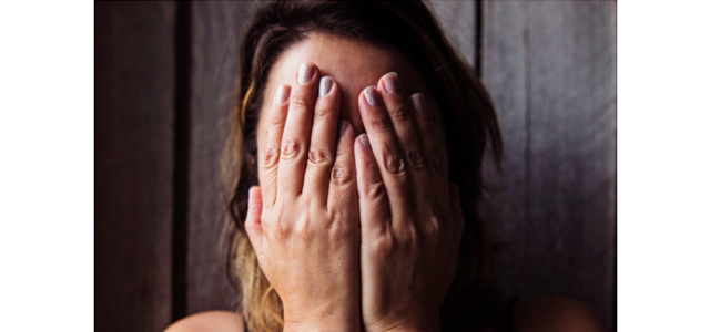 Woman covering her face with her hands due to difficulty from brain fog symptoms of periods